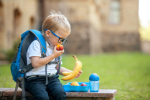 Cute,schoolboy,eating,outdoors,the,school,from,plastick,lunch,boxe.