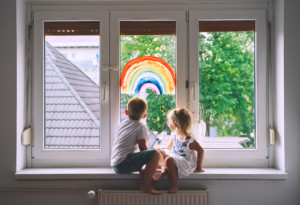 Cute,little,children,on,background,of,painting,rainbow,on,window.